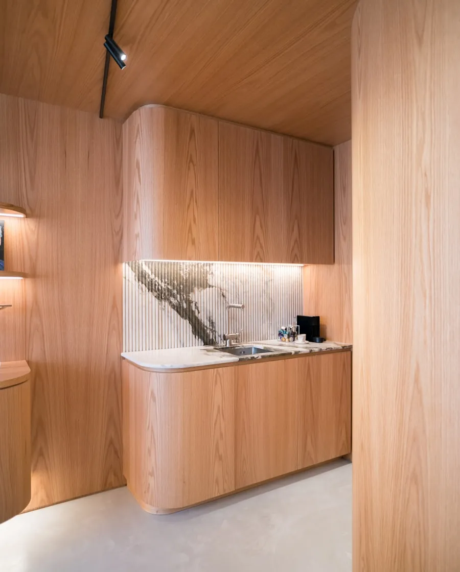 Cuisine d’atelier en frêne huilé, façades cintrées et plan de travail en pierre bleue.
